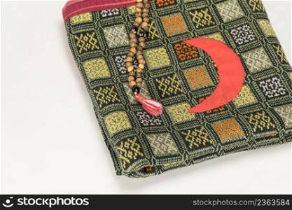 Muslim prayer beads on the prayer Mat with the Crescent symbol on   white background. Islamic and Muslim concepts. Ramadan, the Muslim rosary