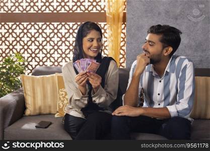 Muslim wife counting money and looking at her husband with smile