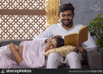 Muslim woman lying on her husband lap on sofa and husband caressing her head