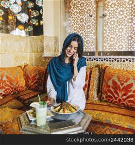 muslim woman making phone call restaurant