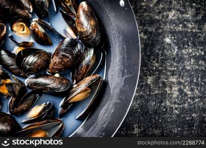 Mussels are cooked in a pot of water. On a black background. High quality photo. Mussels are cooked in a pot of water. 