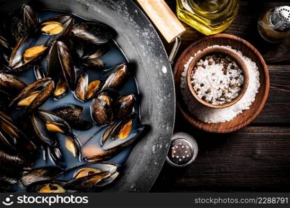 Mussels in a pot of water. On a wooden background. High quality photo. Mussels in a pot of water.