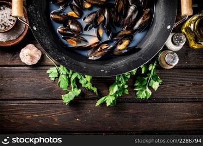 Mussels in a saucepan with parsley and spices. On a wooden background. High quality photo. Mussels in a saucepan with parsley and spices. 