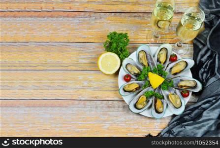 Mussels with herbs with lemon parsley in the table setting / Steamed mussels and wine glass served on white plate seafood sauce delicious on dining table restaurant