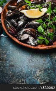 Mussels with lemon and ingredients for cooking in wooden plate on rustic background, top view, place for text