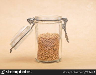 Mustard seeds in glass on brown background