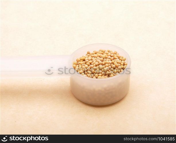 Mustard seeds in measuring spoon on brown background