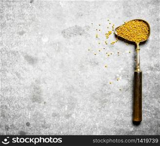 Mustard seeds in the old spoon. On the stone table.. Mustard seeds in the old spoon.
