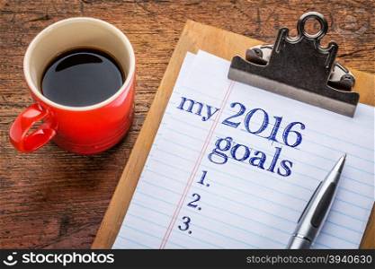 my 2016 goals list on clipboard and coffee against grunge wood desk