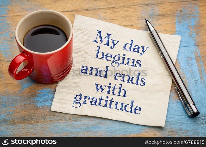 My day begins and ends with gratitude - positive affirmation words - handwriting on a napkin with a cup of coffee