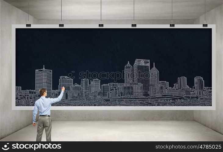 My development project. Rear view of man engineer drawing on chalkboard