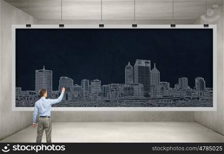 My development project. Rear view of man engineer drawing on chalkboard