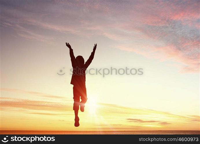 My happy childhood. Silhouette of jumping kid boy over sunset background