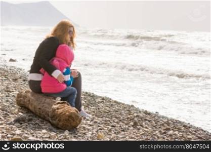 My mother and five year old daughter sitting on the beach, my mother hugged her frozen girl