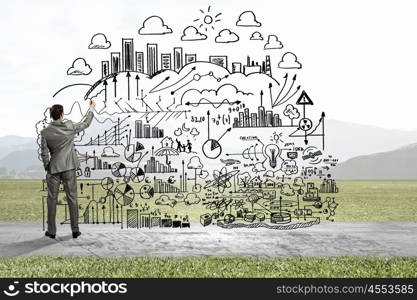 My strategy plan. Back view image of businessman drawing sketches on wall