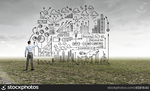 My strategy plan. Back view image of businessman drawing sketches on wall