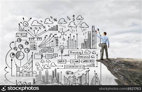 My strategy plan. Back view image of businessman drawing sketches on wall