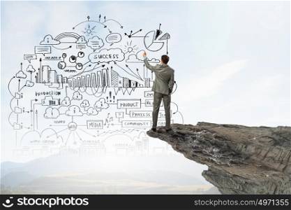 My strategy plan. Back view image of businessman drawing sketches on wall