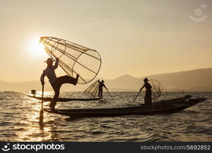 Myanmar travel attraction landmark - three traditional Burmese fishermen at Inle lake, Myanmar famous for their distinctive one legged rowing style