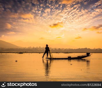 Myanmar travel attraction landmark - traditional Burmese fisherman sihouettes at Inle lake on sunset, Myanmar famous for their distinctive one legged rowing style