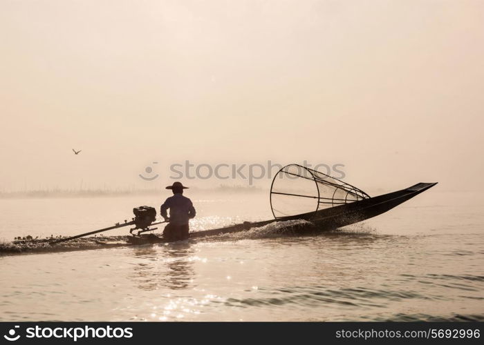 Myanmar travel attraction landmark - Traditional Burmese fisherman with fishing net at Inle lake in speeding motor boat