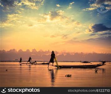 Myanmar travel attraction landmark - traditional Burmese fishermen sihouettes at Inle lake on sunset, Myanmar famous for their distinctive one legged rowing style