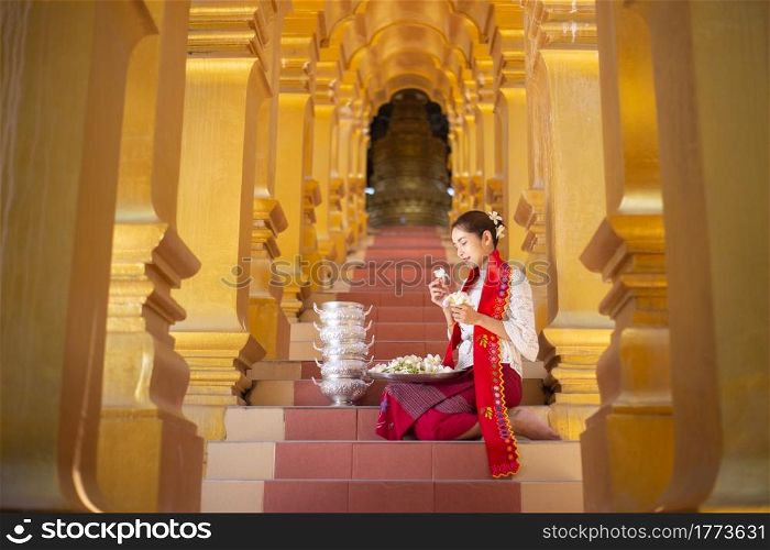 Myanmar women holding flowers at a temple. Southeast Asian young girls with burmese traditional dress visiting a Buddihist temple