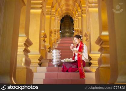 Myanmar women holding flowers at a temple. Southeast Asian young girls with burmese traditional dress visiting a Buddihist temple