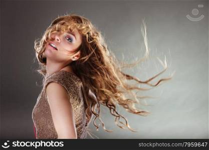 Mysterious enigmatic attractive woman girl.. Mysterious enigmatic woman in studio on grey. Young intriguing attractive girl with flying long curly hair in motion. Shining light.