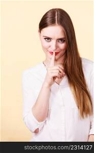 Mysterious, enigmatic brunette woman showing silence gesture with finger close to mouth.. Mysterious woman showing silence gesture with finger