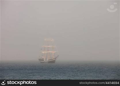 Mysterious sailing ship surrounded fog sailing on blue ocean
