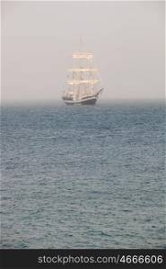 Mysterious sailing ship surrounded fog sailing on blue ocean