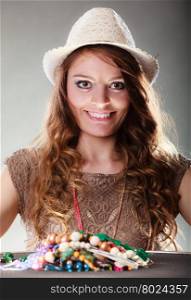 Mysterious woman with jewelry necklaces beads.. Pretty young mysterious woman in hat with many plentiful of precious jewelry necklaces beads. Portrait of gorgeous fashion girl in studio on gray.