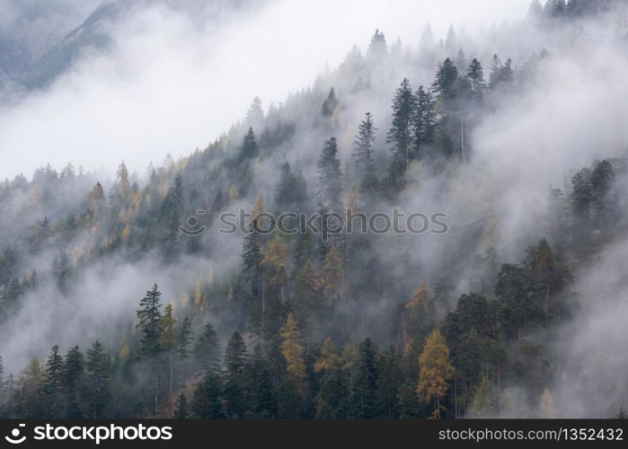 Mystic cloudy and foggy autumn alpine mountain slopes scene. Austrian Lienzer Dolomiten Alps. Peaceful picturesque traveling, seasonal, nature and countryside beauty concept scene.