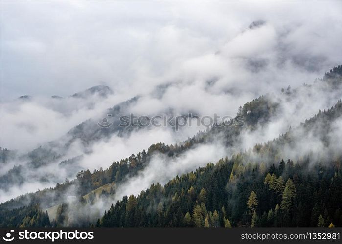 Mystic cloudy and foggy autumn alpine mountain slopes scene. Austrian Lienzer Dolomiten Alps. Peaceful picturesque traveling, seasonal, nature and countryside beauty concept scene.