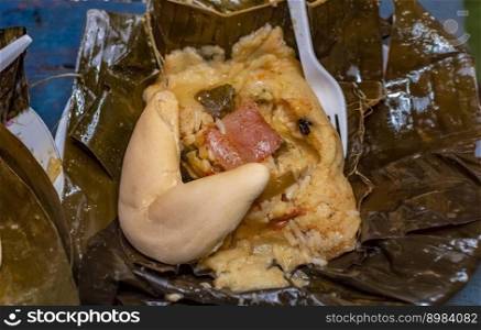 Nacatamal served with bread in a banana leaf on the table. Traditional Nacatamal served in banana leaf, Nicaraguan Nacatamal with bread on the table, Traditional Venezuelan Hallaca served