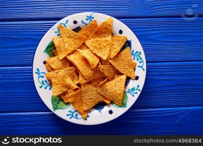 Nachos chips on mexican plate over blue wooden table