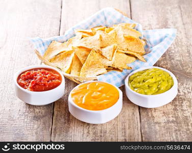 nachos with various sauces on wooden table