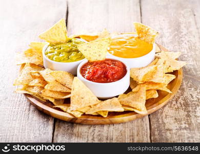 nachos with various sauces on wooden table