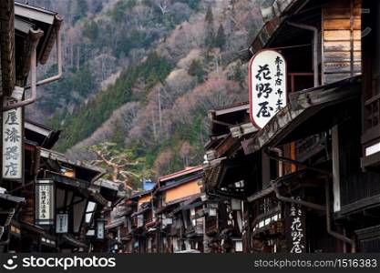 Nagano, Japan - April 14, 2019: Narai-juku preserved historic post town, closeup wooden houses with banner, Kiso valley, Shiojiri. Famous travel destination or landmark in Chubu.