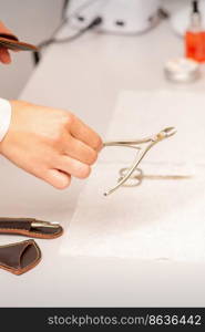 Nail nippers in the hand of female manicure master putting to the towel before nail care in manicure salon. Nail nippers in the hand of female manicure master putting to the towel before nail care in manicure salon.
