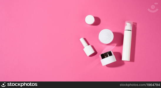 nail polish, jar and empty white plastic tubes for cosmetics on a pink background. Packaging for cream, gel, serum, advertising and product promotion, top view, copy space