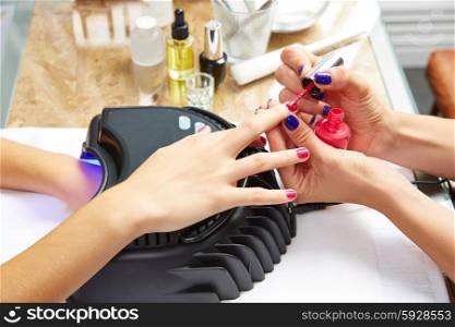 Nails painting with UV dry lamp in blue light woman hands at nail salon