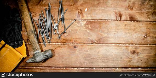 Nails with hammer and gloves. On a wooden background. High quality photo. Nails with hammer and gloves.