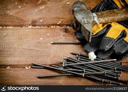 Nails with hammer and gloves. On a wooden background. High quality photo. Nails with hammer and gloves.