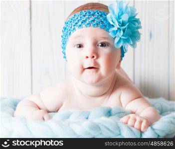 Naked baby girl lying on the soft curtain with blue bandage around her head. Cute baby girl with blue bandage