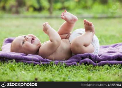 Naked little boy is looking on nature and playing. Little boy on lawn