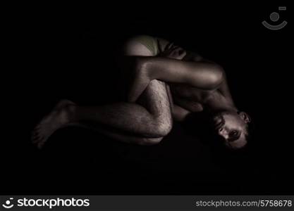 Naked lonely young man lying on the floor