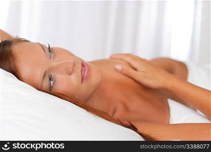 Naked woman lying in white bed, shallow depth-of-field