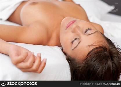 Naked woman sleeping in white bed, shallow DOF